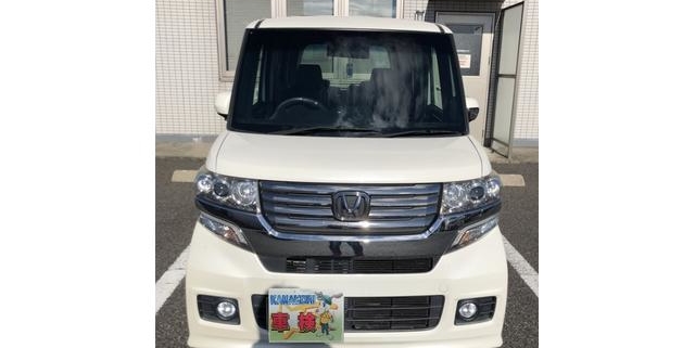 ホンダ N-BOX カスタム（JF1型）を整備工場の駐車場で正面から撮影した高解像度の写真。メッキグリルとフォグランプが際立つスタイリッシュな軽自動車