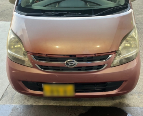 フロントから見たダイハツ ムーヴ（L150系）の外観。経年劣化によりボンネット塗装が退色しており、車体前方の床には液体の漏れ跡が見られる