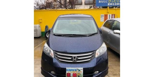駐車場に停車しているホンダ フリードの正面写真。落ち着いたブルーの車体とミニバンらしい広い室内空間が魅力。