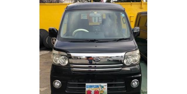 駐車場に停車中のダイハツ アトレー カスタムターボ｜フロントマスクのメッキグリルと丸型フォグランプが特徴の黒い軽ワンボックス