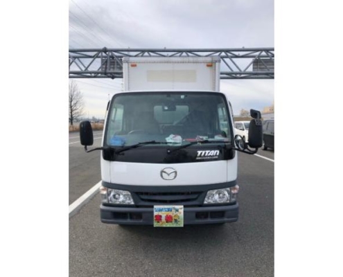 道路上で正面から撮影されたマツダ・タイタンのアルミバントラック。商用利用される中型トラックの外観が分かる画像。