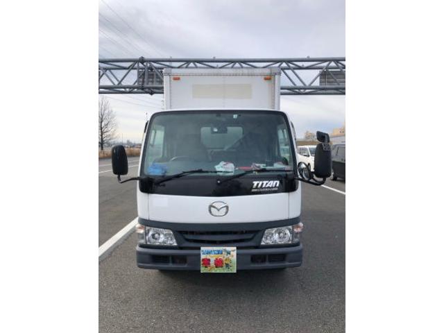 道路上で正面から撮影されたマツダ・タイタンのアルミバントラック。商用利用される中型トラックの外観が分かる画像。